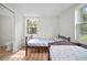 Bright bedroom featuring two twin beds, wood-look flooring, and a window with natural light, adjacent to a bathroom at 820 N Carroll Rd, Lakeland, FL 33801