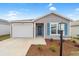 Charming one-story home featuring a one-car garage, blue shutters, landscaped yard, and welcoming front door at 1974 Lockett Ln, The Villages, FL 34762