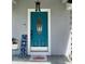 Bright teal front door with decorative glass and welcome mat, enhanced by a charming lantern at 858 Lafayette Ln, Lakeland, FL 33805