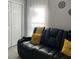 Comfortable living room with a plush black sofa, bright yellow accent pillows, and natural light from the sheer-curtained window at 858 Lafayette Ln, Lakeland, FL 33805