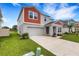 Modern two-story home with a two-car garage, a well-maintained lawn, and views of the water at 4381 Pumice Dr, Lakeland, FL 33811