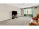 Carpeted living room featuring a large window, a flat screen television, and comfortable seating at 4381 Pumice Dr, Lakeland, FL 33811
