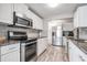 Bright kitchen features white cabinetry, stainless steel appliances, granite counters and wood grain tile floors at 5006 Lodgewood Dr, Lakeland, FL 33810