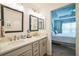 Bathroom featuring double sinks, grey cabinets, large mirrors, and an open view into the bedroom at 6922 Wendy Way, The Villages, FL 34762