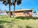 This backyard features palm trees, a lawn, a neutral painted home, and outdoor seating at 703 New York Ave, South Daytona, FL 32119