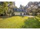 The backyard view of the two-story home with mature trees and a spacious green lawn at 9401 Cat Track Trl, Lake Wales, FL 33898