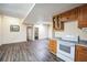 Open-concept kitchen with wood cabinets, white appliances, and laminate flooring at 9401 Cat Track Trl, Lake Wales, FL 33898