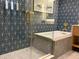 Bathroom featuring elegant blue and white patterned walls, glass shower doors, and a luxurious soaking tub at 3151 Sunset Walk Dr # 314, Kissimmee, FL 34747