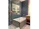 Modern bathroom featuring a soaking tub, glass shower, blue patterned wall, and a framed art print at 3151 Sunset Walk Dr # 314, Kissimmee, FL 34747