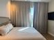 Bright bedroom with a king-size bed, soft curtains, and a mounted flat-screen TV at 3151 Sunset Walk Dr # 314, Kissimmee, FL 34747