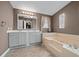 Bathroom featuring double sinks, vanity, a jacuzzi bathtub, and a decorative window at 1717 Lilly Ln, Lady Lake, FL 32159