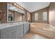 Bathroom featuring double sinks, vanity, a jacuzzi bathtub, and a decorative window at 1717 Lilly Ln, Lady Lake, FL 32159