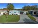 Single-story home features a well-manicured lawn and an inviting carport, with a light blue facade at 1717 Lilly Ln, Lady Lake, FL 32159