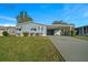 Charming single-story home features a well-manicured lawn and an inviting carport, with a light blue facade at 1717 Lilly Ln, Lady Lake, FL 32159