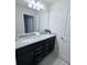 Double sink bathroom featuring granite counters, dark wood cabinets, and a large mirror at 627 Jasmine Ln, Davenport, FL 33897