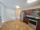 Well-lit kitchen featuring stainless steel appliances, dark wood cabinets, and stylish tile flooring at 6187 Brookhill Cir, Orlando, FL 32810