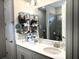 Bathroom with double sinks, modern fixtures, a large mirror, and tiled shower behind a glass door at 2188 Palm Tree Dr, Kissimmee, FL 34759