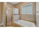 Bright bathroom with a glass-enclosed shower, tub, and decorative glass block window at 6327 Ashley Dr, Lakeland, FL 33813