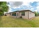 Rear exterior view featuring a sunroom addition, manicured lawn, and mature landscaping at 9761 Sw 74Th Pl, Ocala, FL 34481