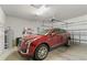 Spacious garage featuring a red SUV, storage shelving, and a functional garage door opener at 9761 Sw 74Th Pl, Ocala, FL 34481