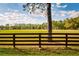 Expansive green pasture and wooden fence with a large shade tree on a sunny day at 4942 Cr 300, Lake Panasoffkee, FL 33538