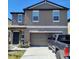 A view of a two-story home featuring a two-car garage, manicured landscaping, and a modern architectural design at 2244 Teneroc Trl, Lakeland, FL 33805