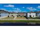 Backyard view with green grass, white picket fence, and blue sky reflected in a beautiful community pond at 2244 Teneroc Trl, Lakeland, FL 33805