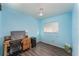 Bedroom has light blue walls, wood floors, desk, and ceiling fan at 520 S Orange Ave, Fort Meade, FL 33841