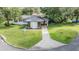Inviting single-story home with an orange front door, lush green lawn, and mature trees at 407 W Oak Dr, Lakeland, FL 33803