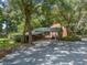 Exterior view of a house with covered parking and a gravel driveway surrounded by mature trees at 4845 Sw 78Th Ave, Bushnell, FL 33513