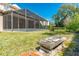 Tranquil backyard featuring mature trees, lush green grass, a stone bench, and a screened-in lanai at 1229 Sebastian Cv, Lake Mary, FL 32746