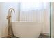 Close up of modern bathtub with gold fixtures and sheer curtains at 1229 Sebastian Cv, Lake Mary, FL 32746
