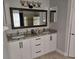Modern bathroom features double vanity with granite countertop and large framed mirror at 2691 Cedaridge Cir, Clermont, FL 34711