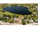 Overhead view of a waterfront property showcasing a home with a red roof, surrounded by serene lake and lush greenery at 5020 Old Lucerne Park Rd, Winter Haven, FL 33881