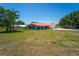 Inviting single-story home with a red roof, lush front yard, and a glimpse of the lake in the background at 5020 Old Lucerne Park Rd, Winter Haven, FL 33881
