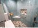 Stylish shower with blue tiling, grab bar, pebble tile floor, and corner seat at 5020 Old Lucerne Park Rd, Winter Haven, FL 33881