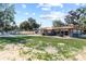 Backyard view featuring a swimming pool, hot tub, lush green grass and a tan home with stone accents at 830 County Rd 457, Lake Panasoffkee, FL 33538