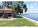 Beautiful backyard with a hot tub, seating, grassy area, and a tranquil lake view and pier at 830 County Rd 457, Lake Panasoffkee, FL 33538