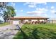 Charming single-story home featuring a stone facade, lush lawn, and an attached garage at 830 County Rd 457, Lake Panasoffkee, FL 33538