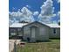 Charming single-story home with a white roof and a front yard under a bright cloudy sky at 102 Se 6Th Ave, Mulberry, FL 33860