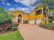 Stunning two-story stucco home featuring a brick driveway, arched entryway, and two-car garage at 254 Chelsea Ave, Davenport, FL 33837