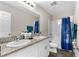 Bathroom featuring double sinks with granite counters and a shower-tub combination with blue shower curtain at 1532 Axel Cir, Winter Haven, FL 33880
