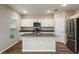 Modern kitchen with white cabinets, stainless steel appliances, an island with seating, and wood-look floors at 1014 Foreshore Ln, Haines City, FL 33844