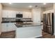 Modern kitchen with white cabinets, stainless steel appliances, an island with seating, and wood-look floors at 1014 Foreshore Ln, Haines City, FL 33844