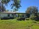 Overgrown backyard with view of the home with a metal roof and some windows at 1122 E Edgewood Dr, Lakeland, FL 33803