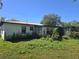Exterior of home with overgrown greenery in backyard and a metal roof at 1122 E Edgewood Dr, Lakeland, FL 33803