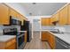 Practical kitchen with wood cabinets, stainless steel appliances, and vinyl flooring at 25 Inconnu Dr, Kissimmee, FL 34759