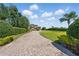 Long brick driveway leading to a luxury home with manicured hedges and lawn, offering a grand entrance at 7769 Summerlake Pointe Blvd, Winter Garden, FL 34787