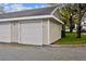 A two-car garage with white doors is nestled on a tree-lined street with meticulous landscaping at 130 Southern Pecan Cir # 205, Winter Garden, FL 34787