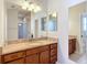 Bathroom featuring a granite-topped vanity with wood cabinets and a large mirror at 2518 Foxbridge Ter, The Villages, FL 32162